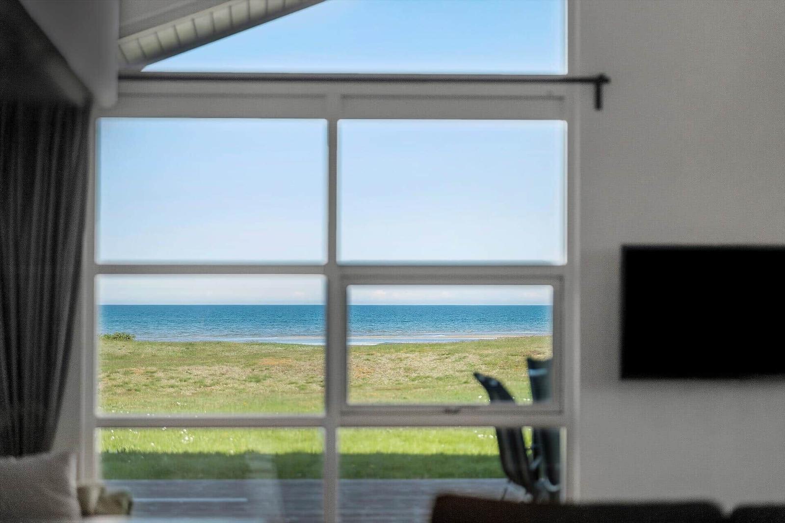 Großes Fenster mit Blick auf Meer und Grasfläche