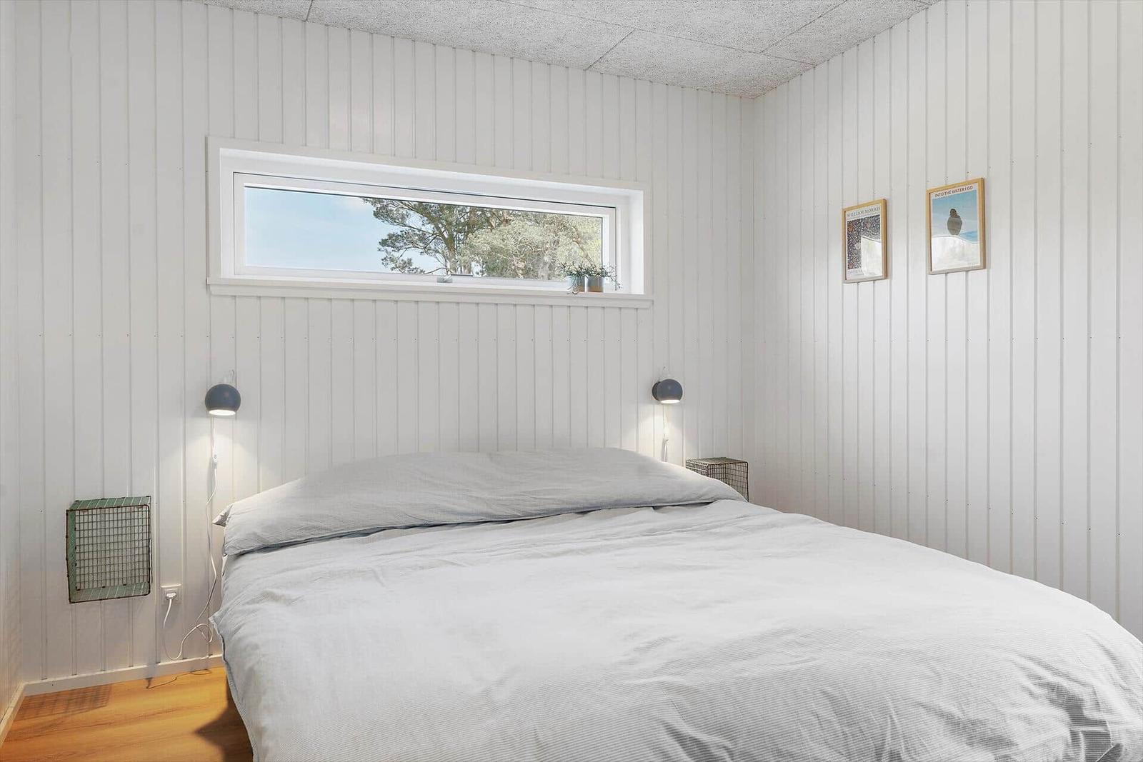 Schlafzimmer mit Bett, Fenster und Wandbildern.