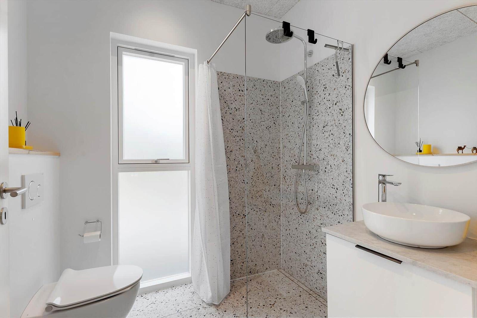 Bad mit Dusche, Waschbecken und Toilette. Terrazzo-Boden und -Wand.