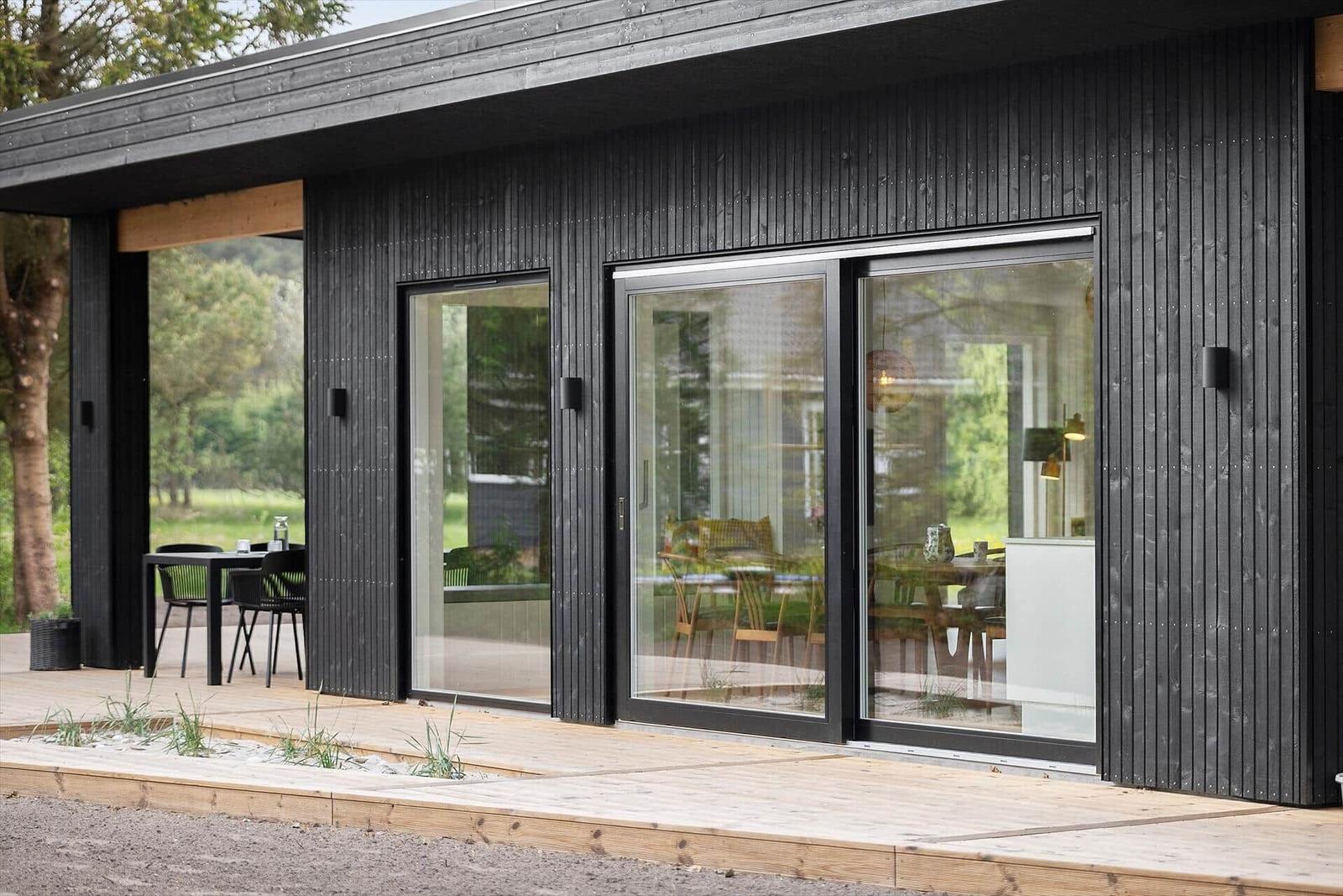 Moderne Villa mit Glasfront und Terrasse. Blick auf Essbereich und Garten.