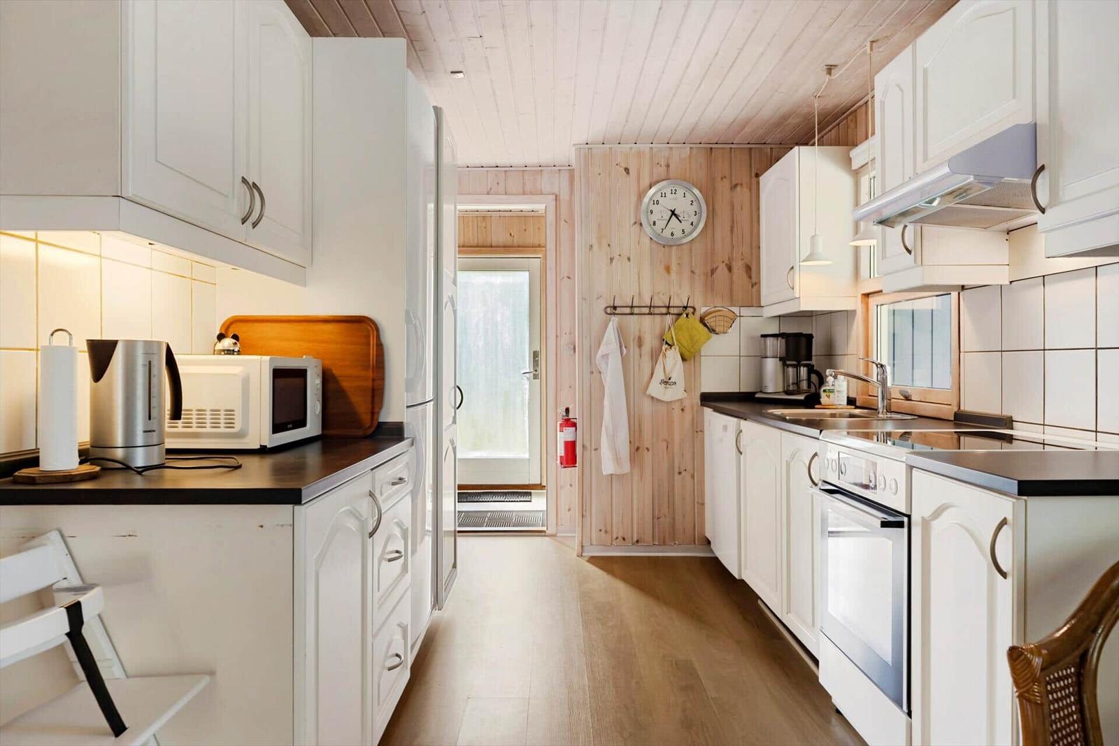 Küche mit weißen Schränken, dunklen Arbeitsflächen und Holzfußboden.
