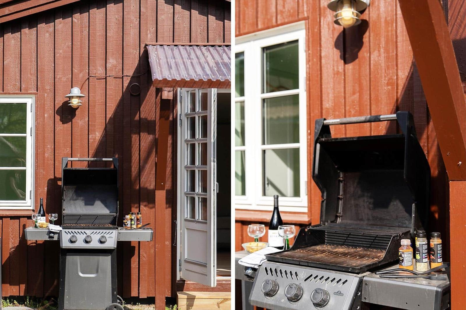 Außenbereich mit Grill, Flasche und Gläsern an roter Holzwand