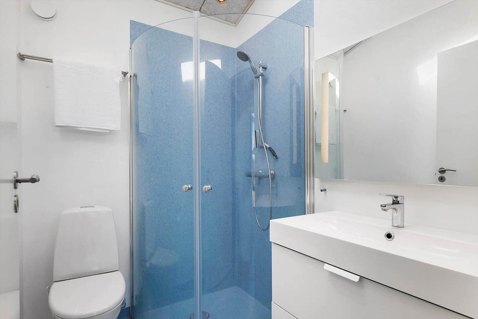 Badezimmer mit Dusche, Waschbecken und Toilette.
