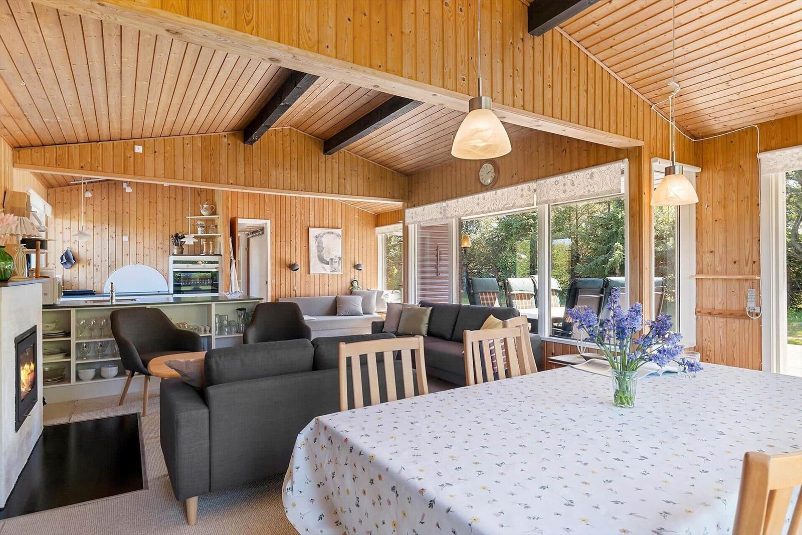 Wohn- und Essbereich mit Holzwand, Esstisch, Sofa und Kamin.