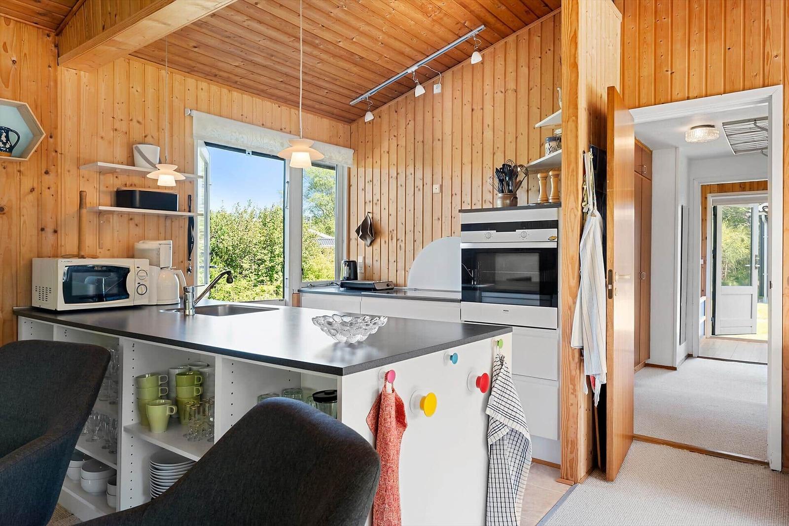 Küche mit Holzwand, Arbeitsplatte und Fenster zur Außenseite.