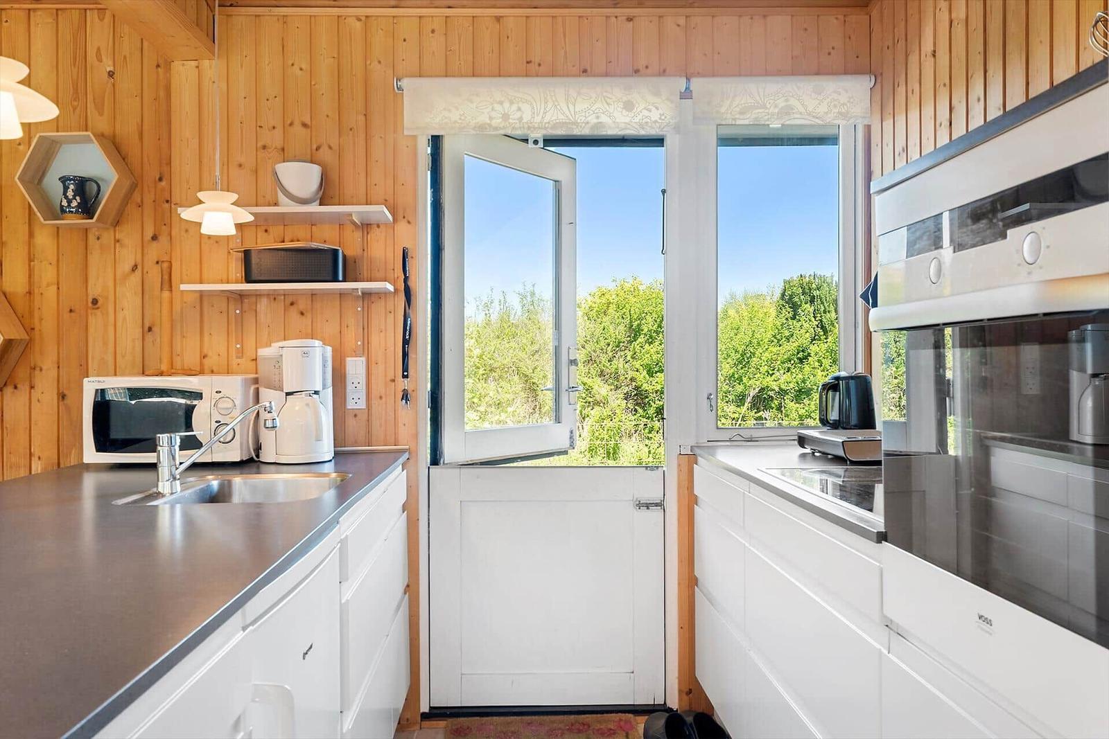 Küche mit Holzwand, Fenster und weißen Schränken
