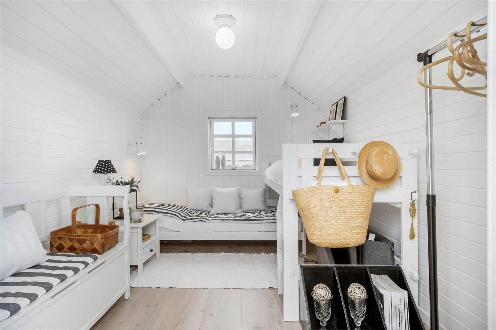 Schlafzimmer mit Doppelbett, Nachttisch und Kleiderschrank. Wandgestell mit Strohhut und Tasche.