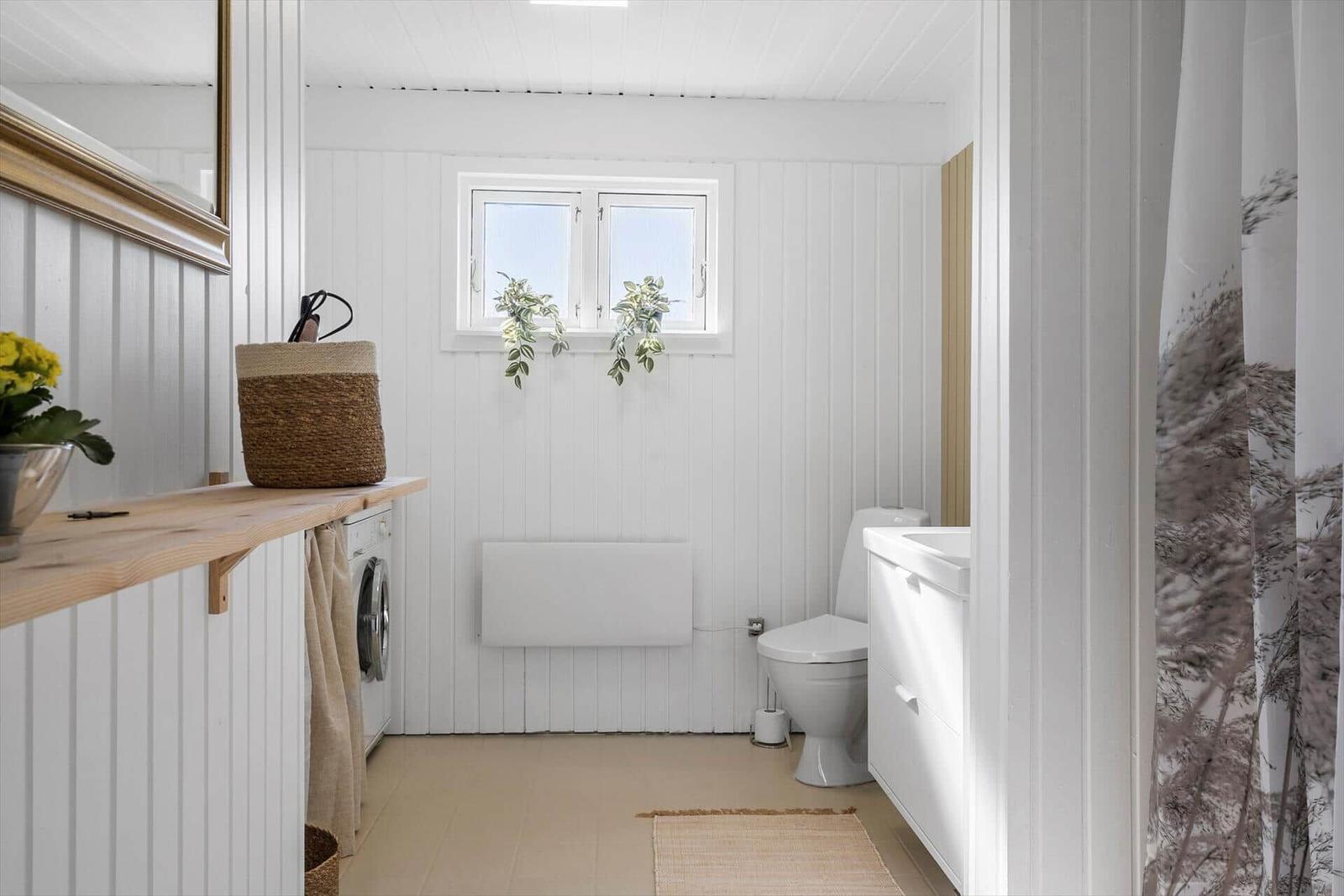 Bathroom with toilet, sink, and window with plants.