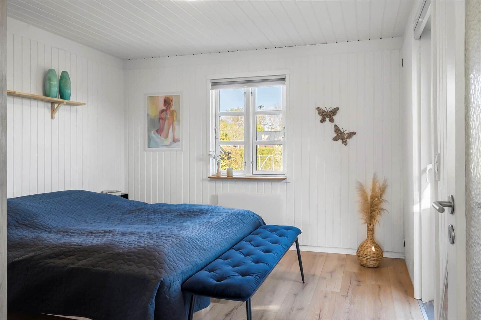 Bedroom with blue quilt, window, and wall decor.