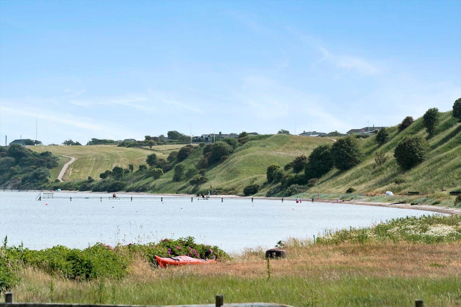 Lakeside with green hills and orange rowboat.