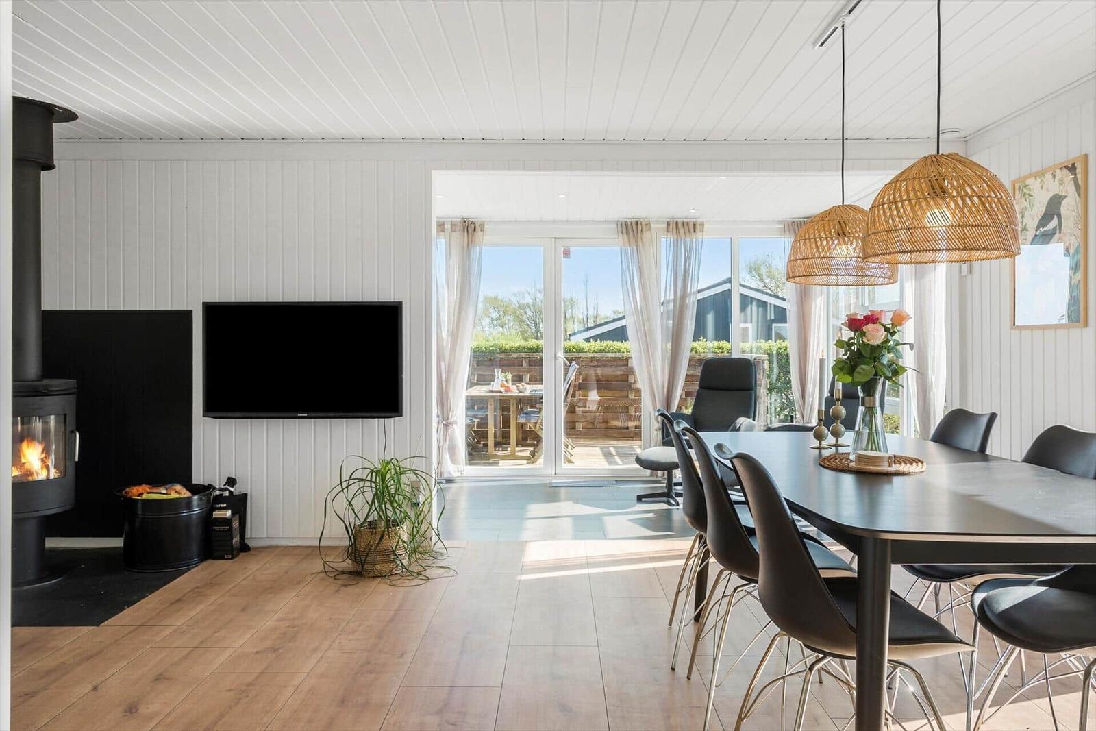 Living and dining area with fireplace, TV, and terrace.