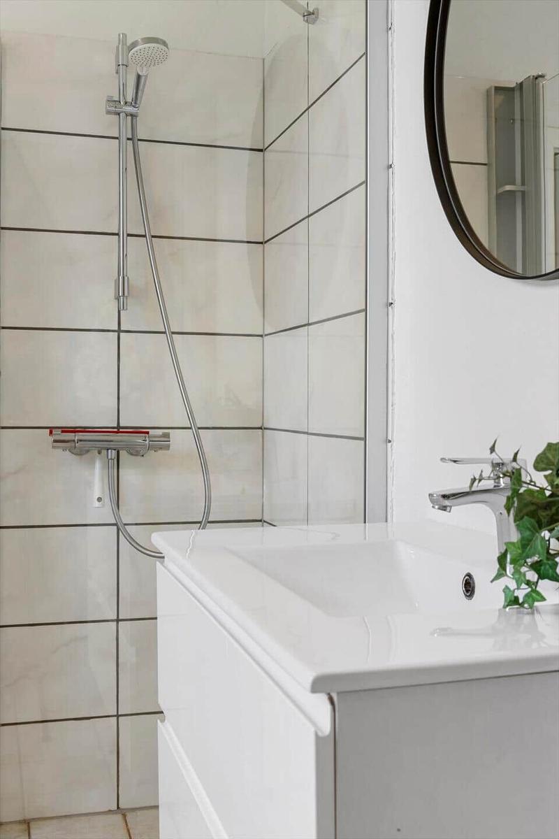 Badezimmer mit Dusche, Waschbecken und Spiegel