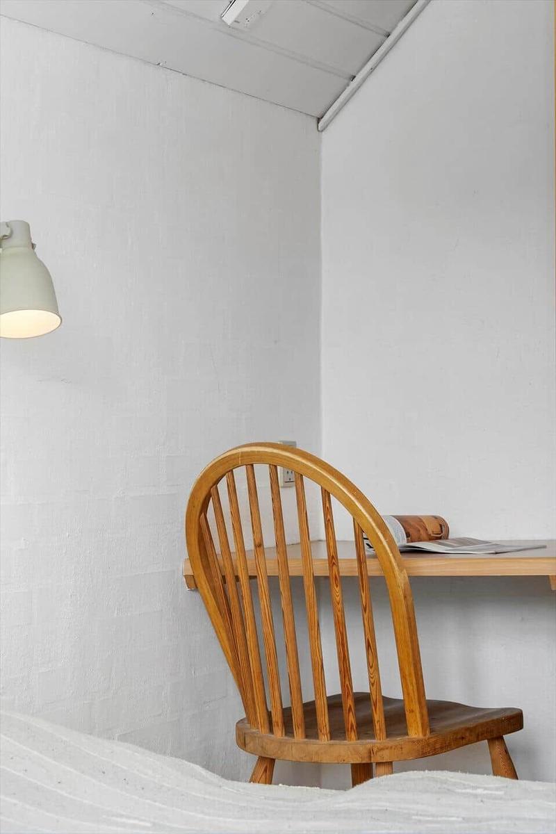 Holzstuhl und Tisch in Ecke mit Wandlampe