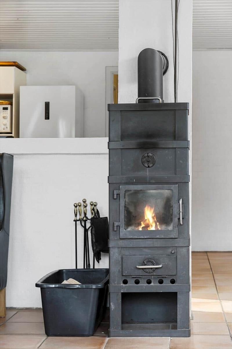 Schwarzer Kaminofen mit brennendem Feuer und Zubehör in Küche