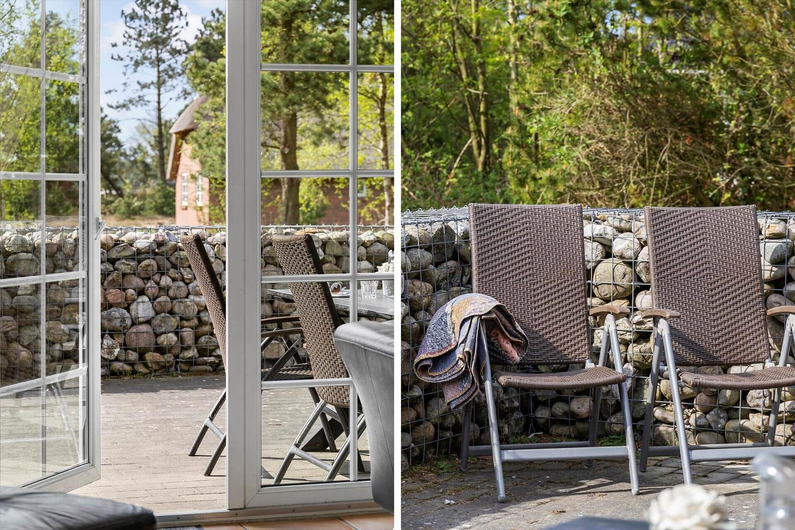 Terrasse mit Sitzgelegenheiten und Steinmauer im Hintergrund.