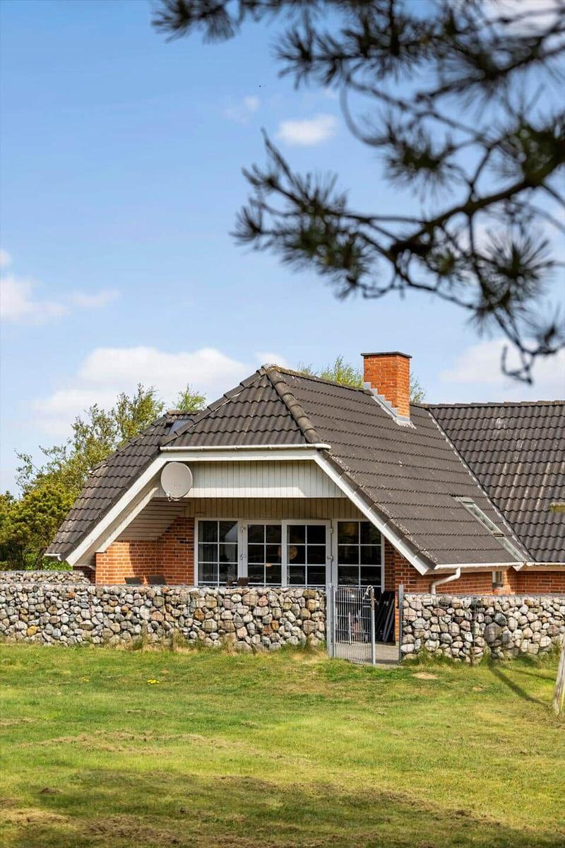 Haus mit Steinmauer und Dachgaube unter blauem Himmel