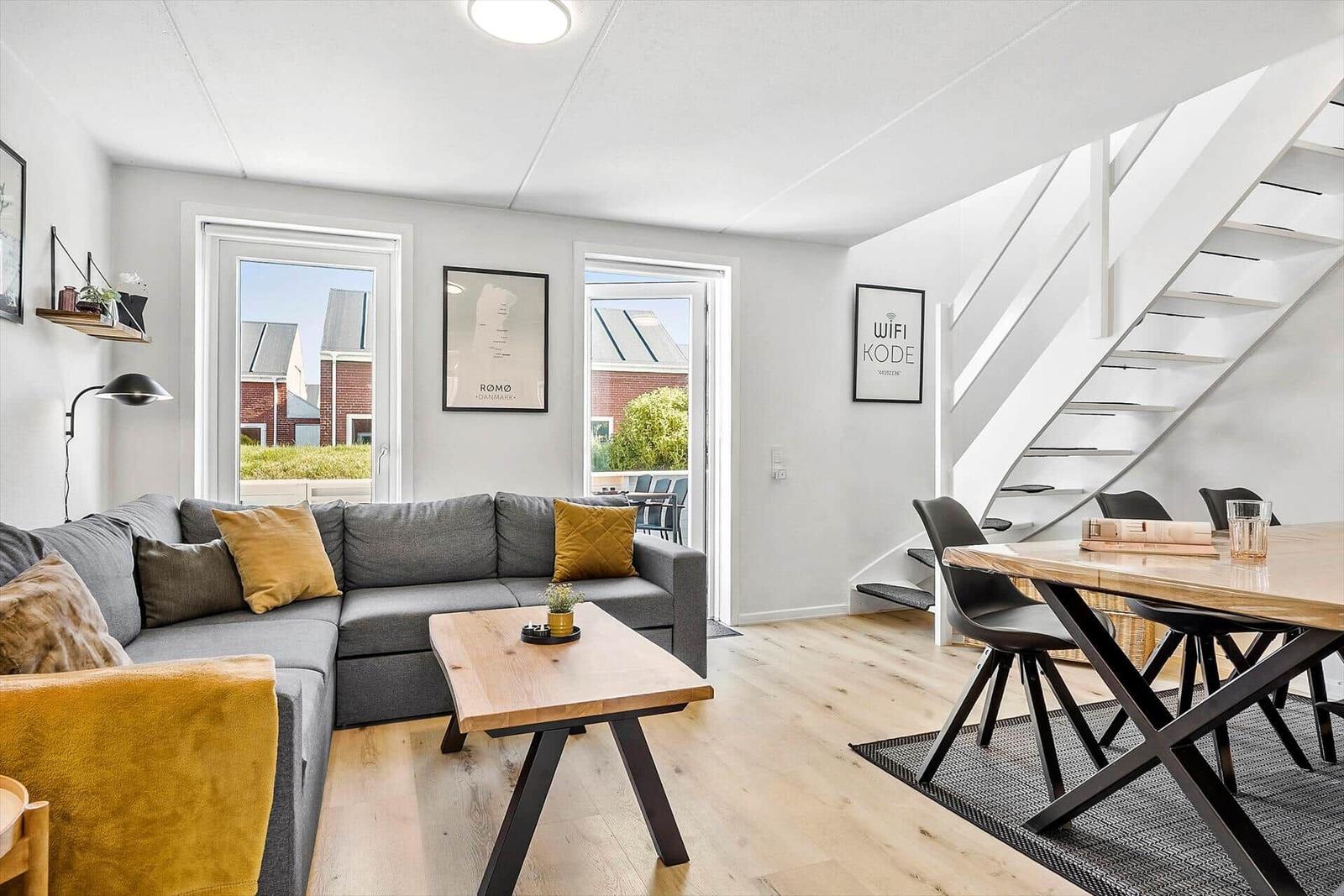 Wohn- und Essbereich mit Sofa, Tisch und Treppe.