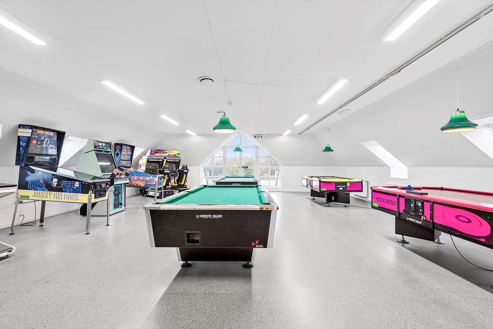 Großes Spielzimmer mit Billardtischen und Arcade-Spielen.