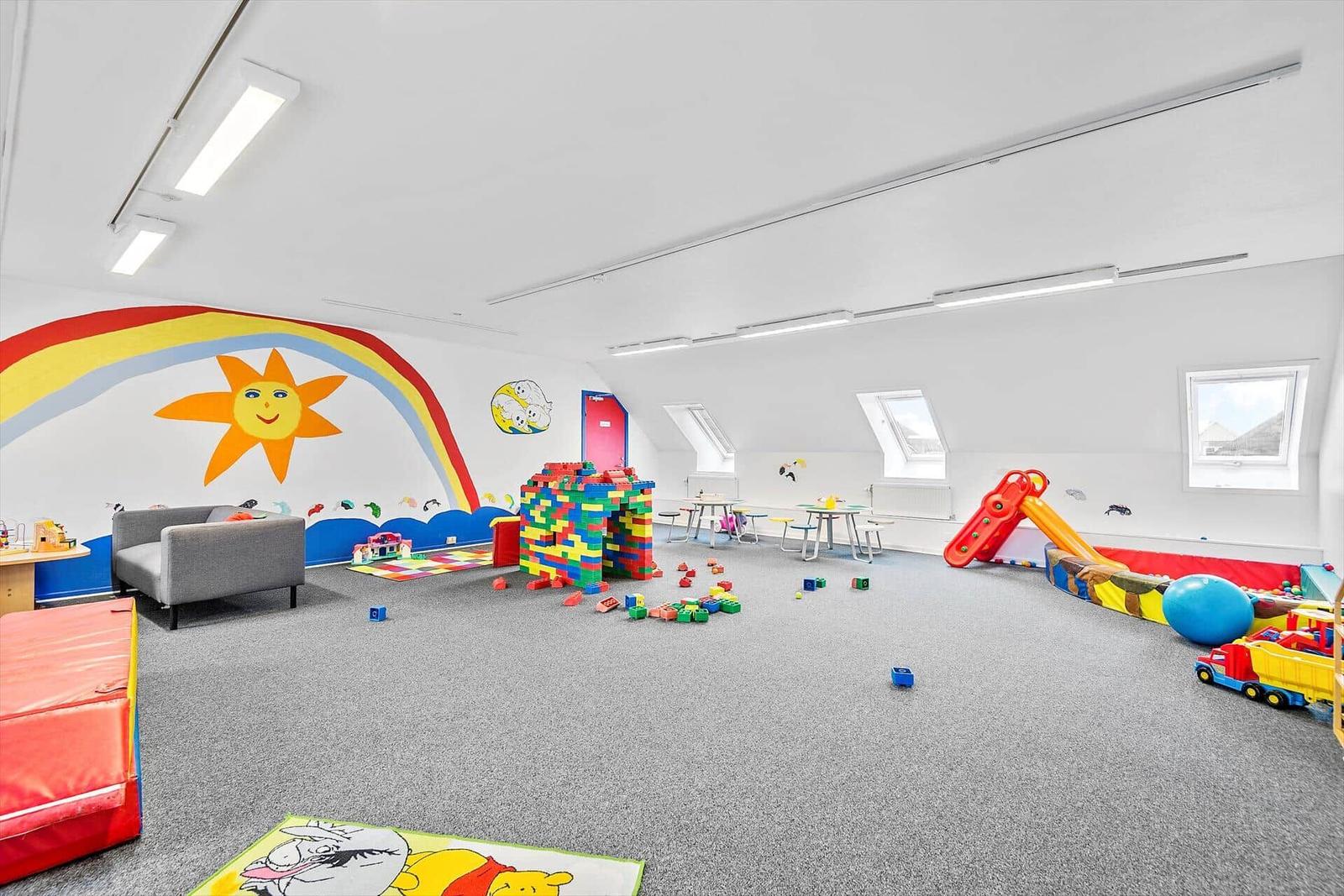 Großer Spielraum mit bunten Spielen, Rutschbahn und Wandmalerei.