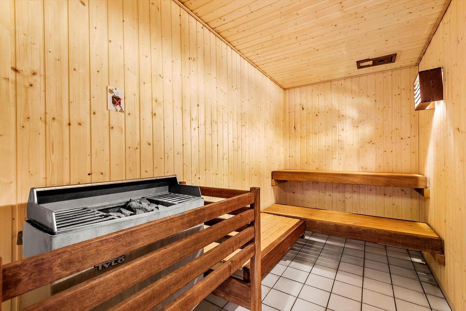 Sauna mit Holzwand, Sitzbänken und Heizung.