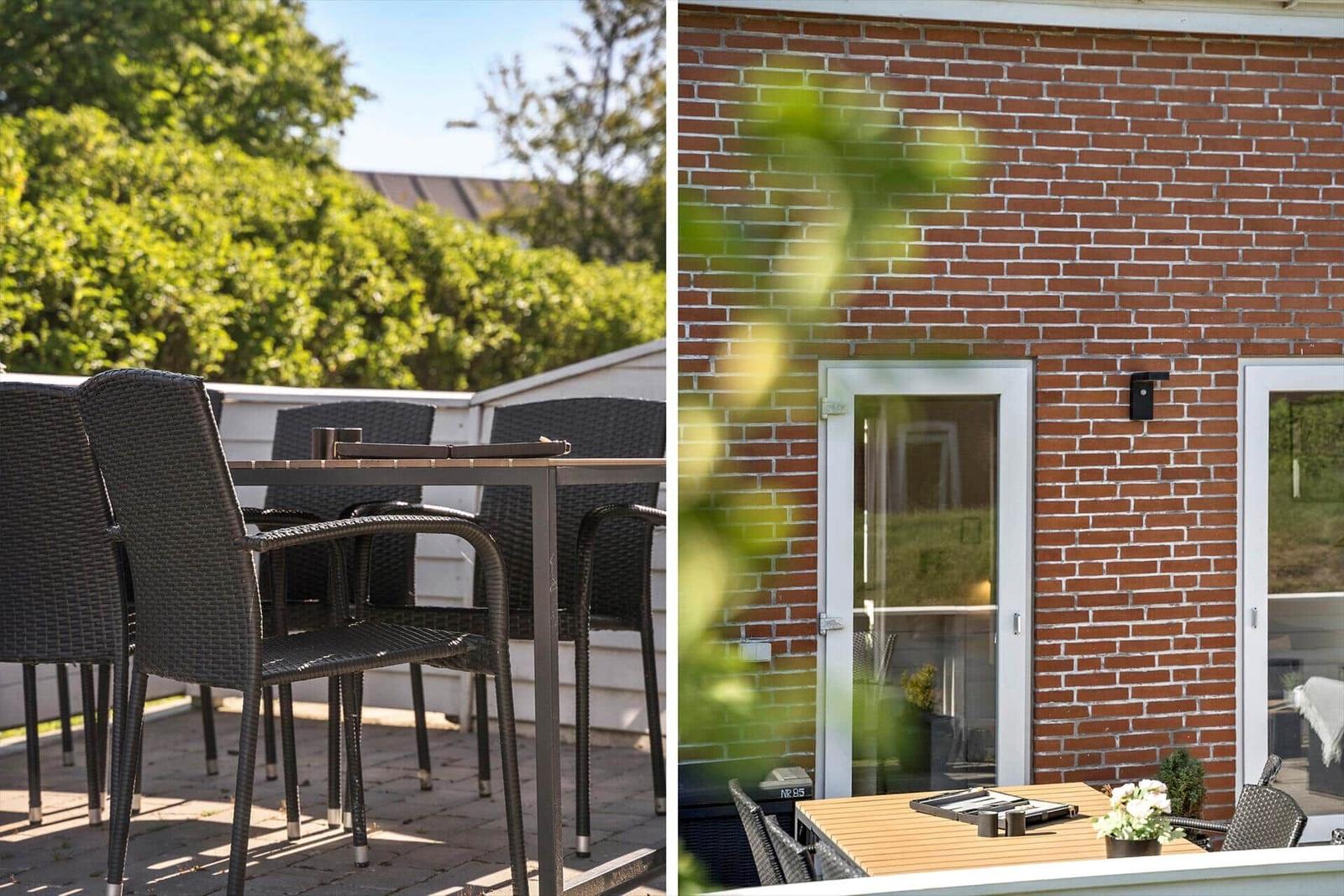 Terrasse mit Tisch und Stühlen, rote Ziegelwand und Glastür