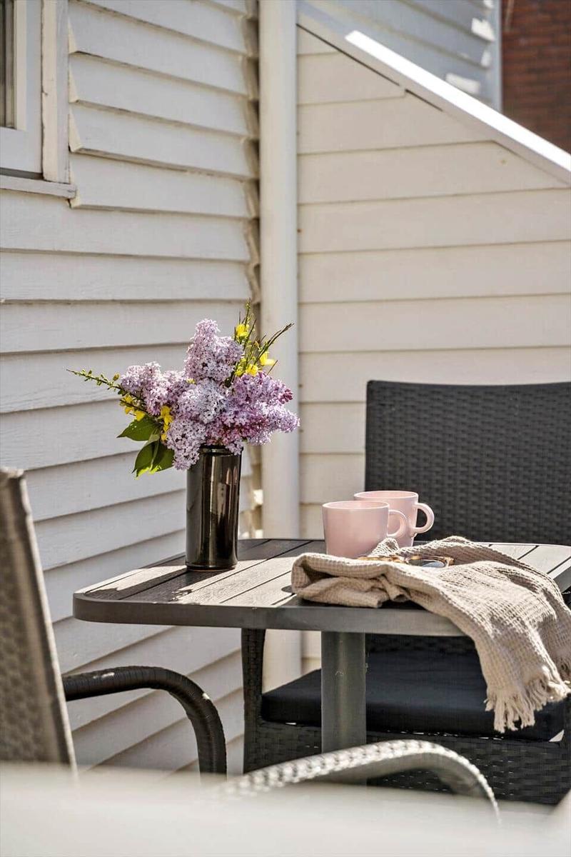 Außenbereich mit Tisch, Stühlen, Blumen und Tassen.