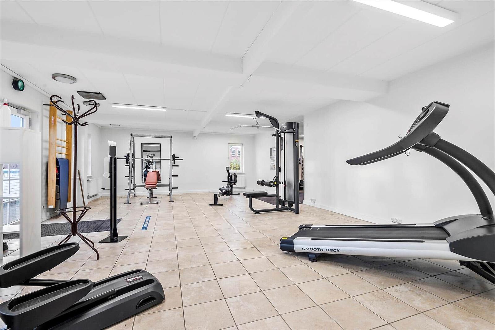 Fitnessraum mit Laufband, Kraftstation und Trainingsgeräten.