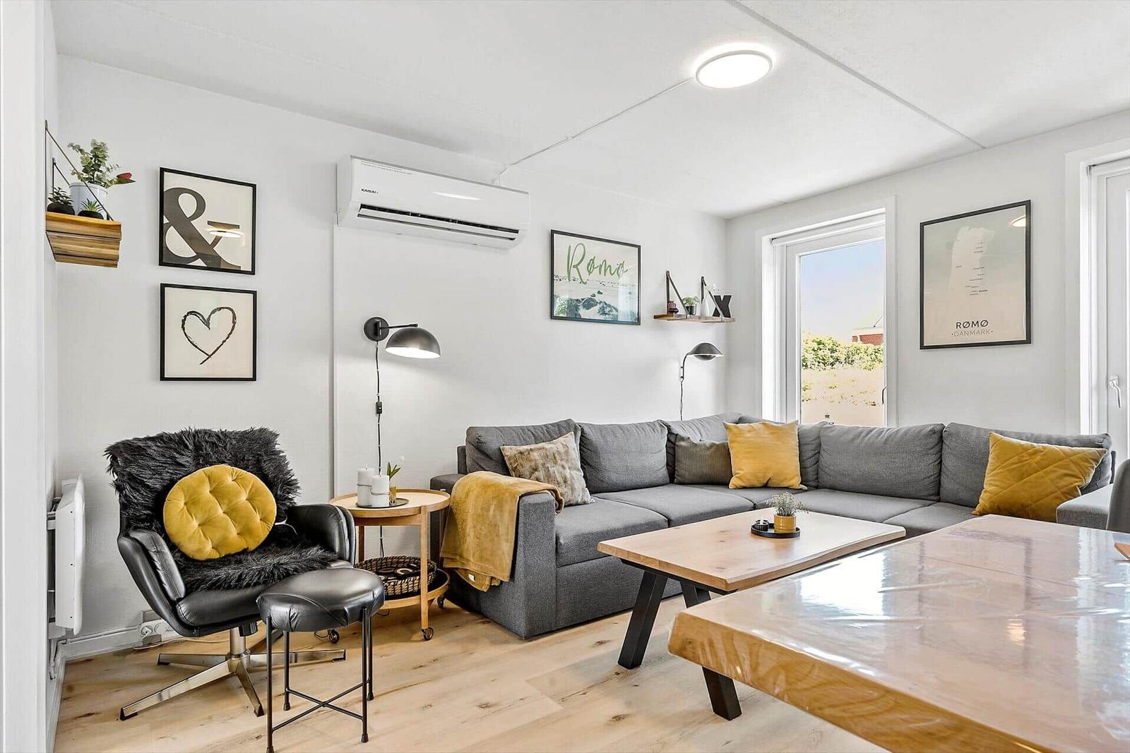 Wohnzimmer mit grauem Sofa, Holztisch und schwarzer Sitzgelegenheit.