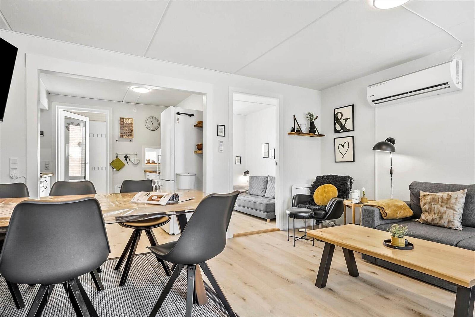 Wohn- und Essbereich mit Sofa, Esstisch und Küchenbereich im Hintergrund.