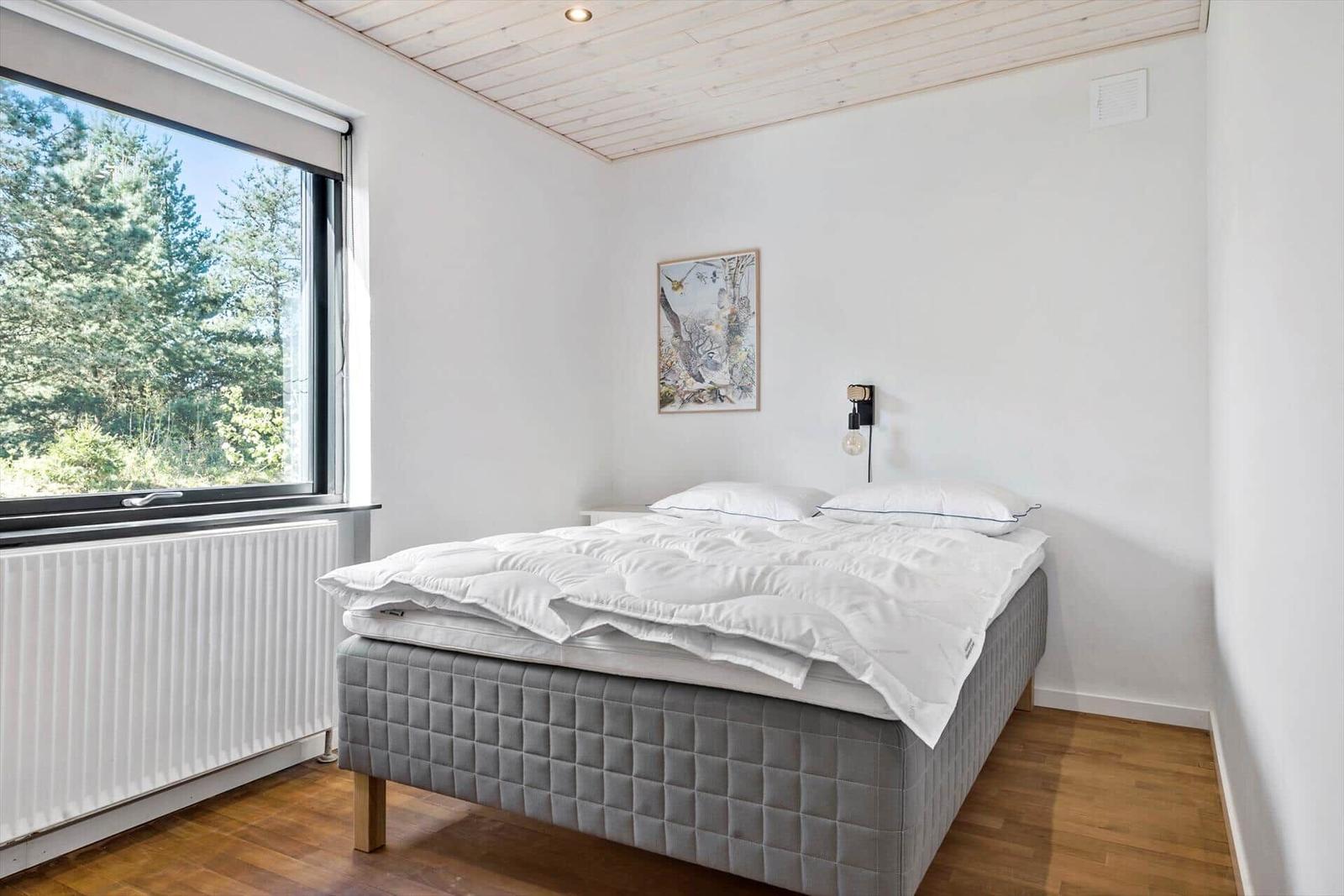 Schlafzimmer mit Bett, Fenster und Holzboden.