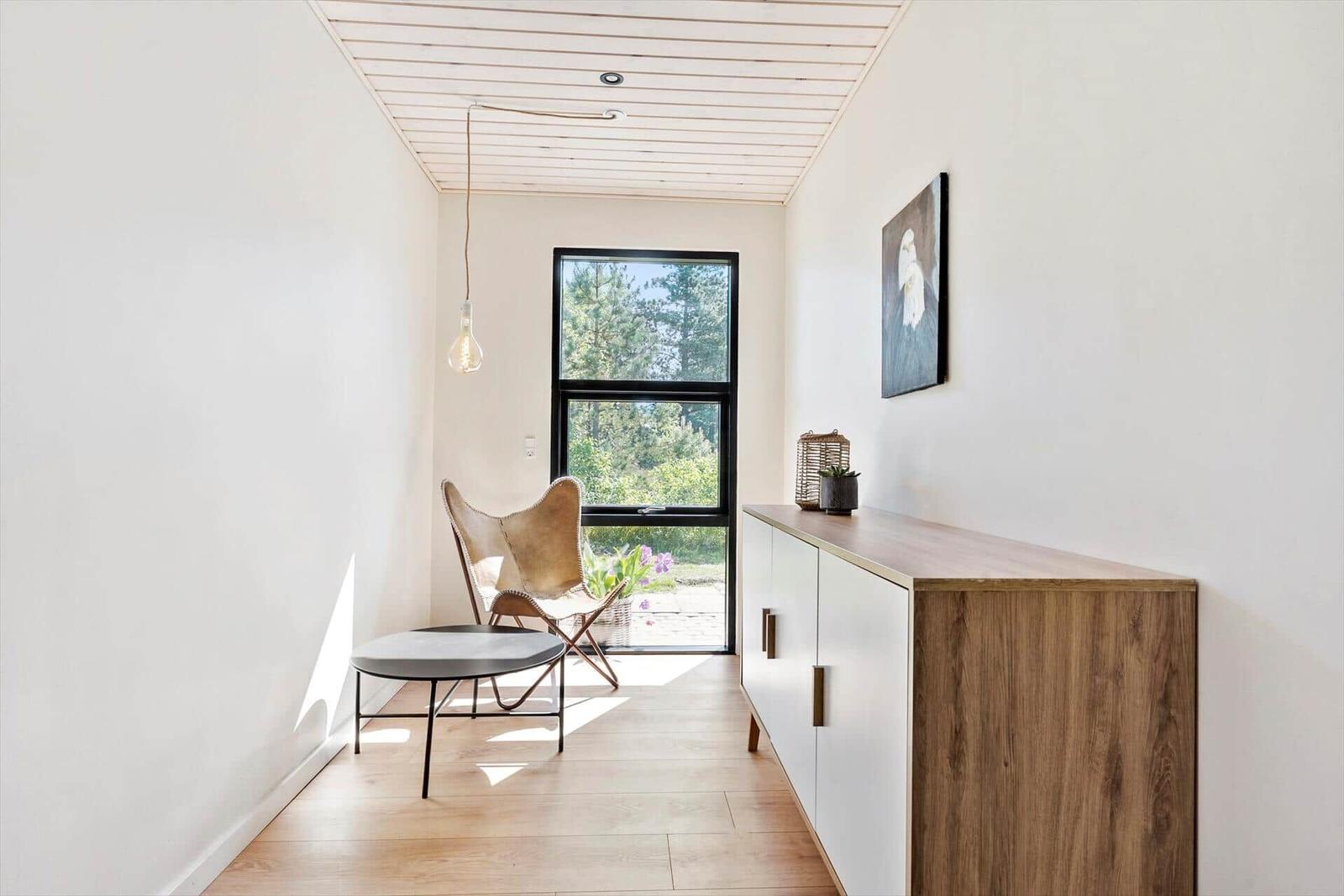 Eingangsbereich mit Stuhl, Tisch und Schrank. Fenster zeigt Garten.
