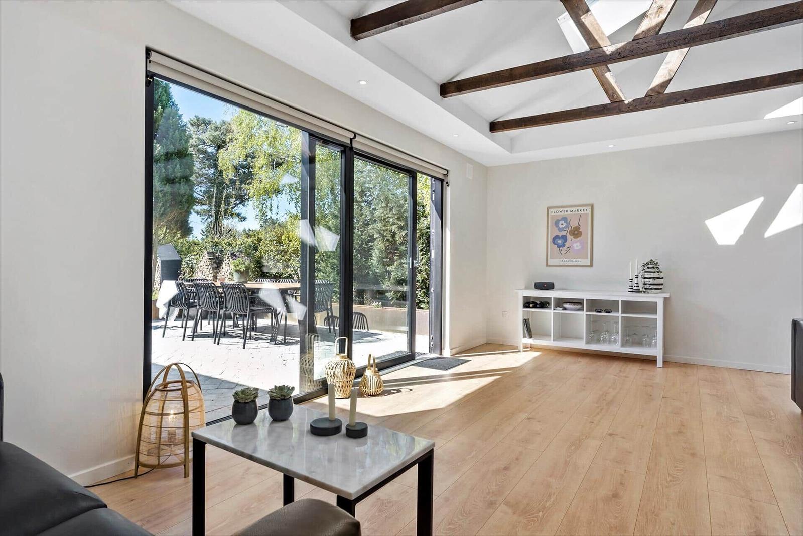 Raum mit Holzboden, großen Glasschiebetüren und Balkon mit Tisch und Stühlen.