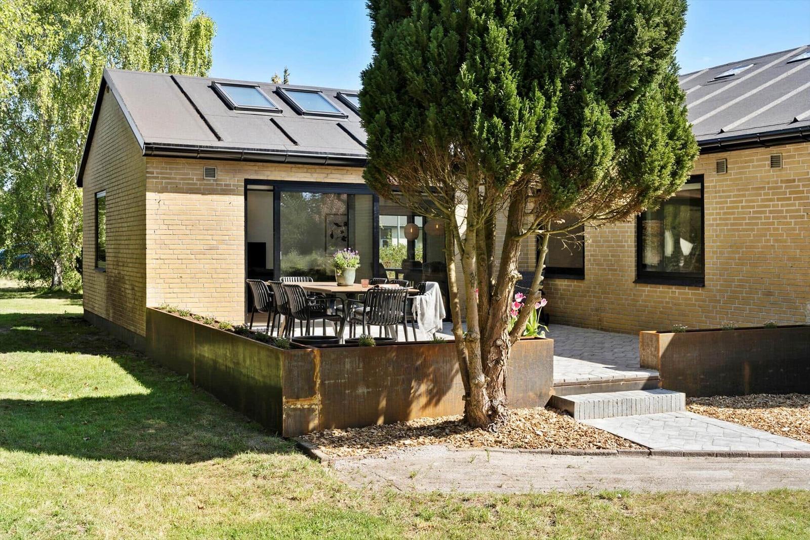 Moderne Villa mit Terrasse, Garten und großen Fenstern.