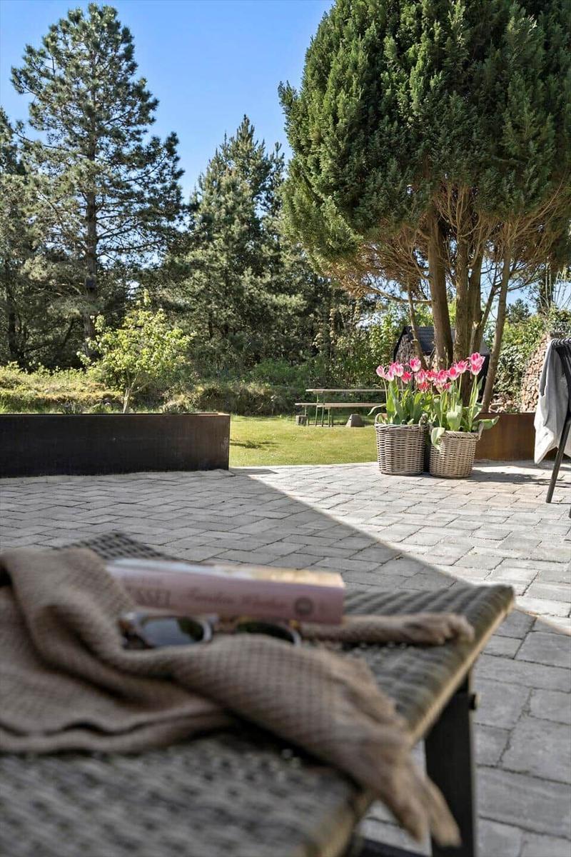 Terrasse mit Blumenkörben und Blick auf grünen Garten