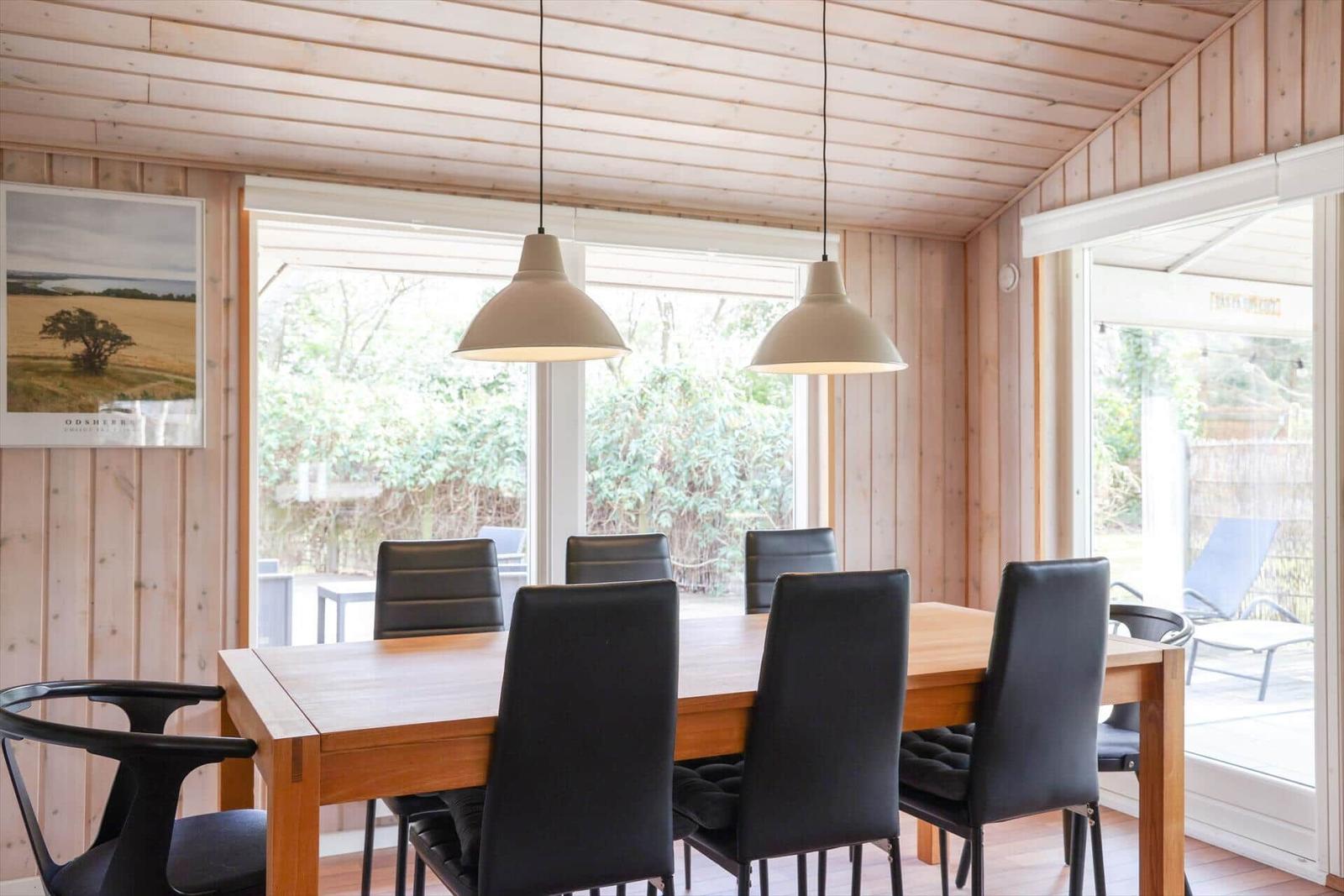 Dining area with wooden table, black chairs, and large windows.