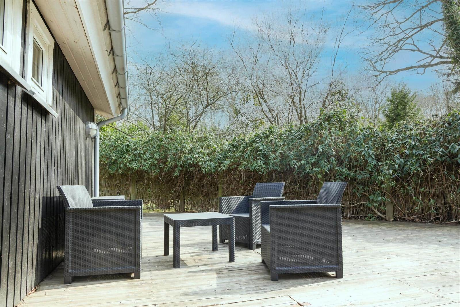 Terrace with garden furniture and view of green hedge