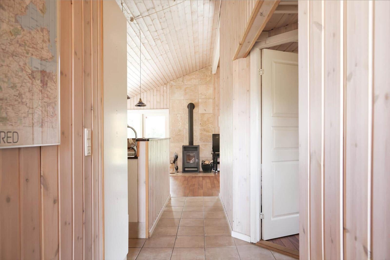 Hall with wooden walls, tiles, and wood stove in the background.