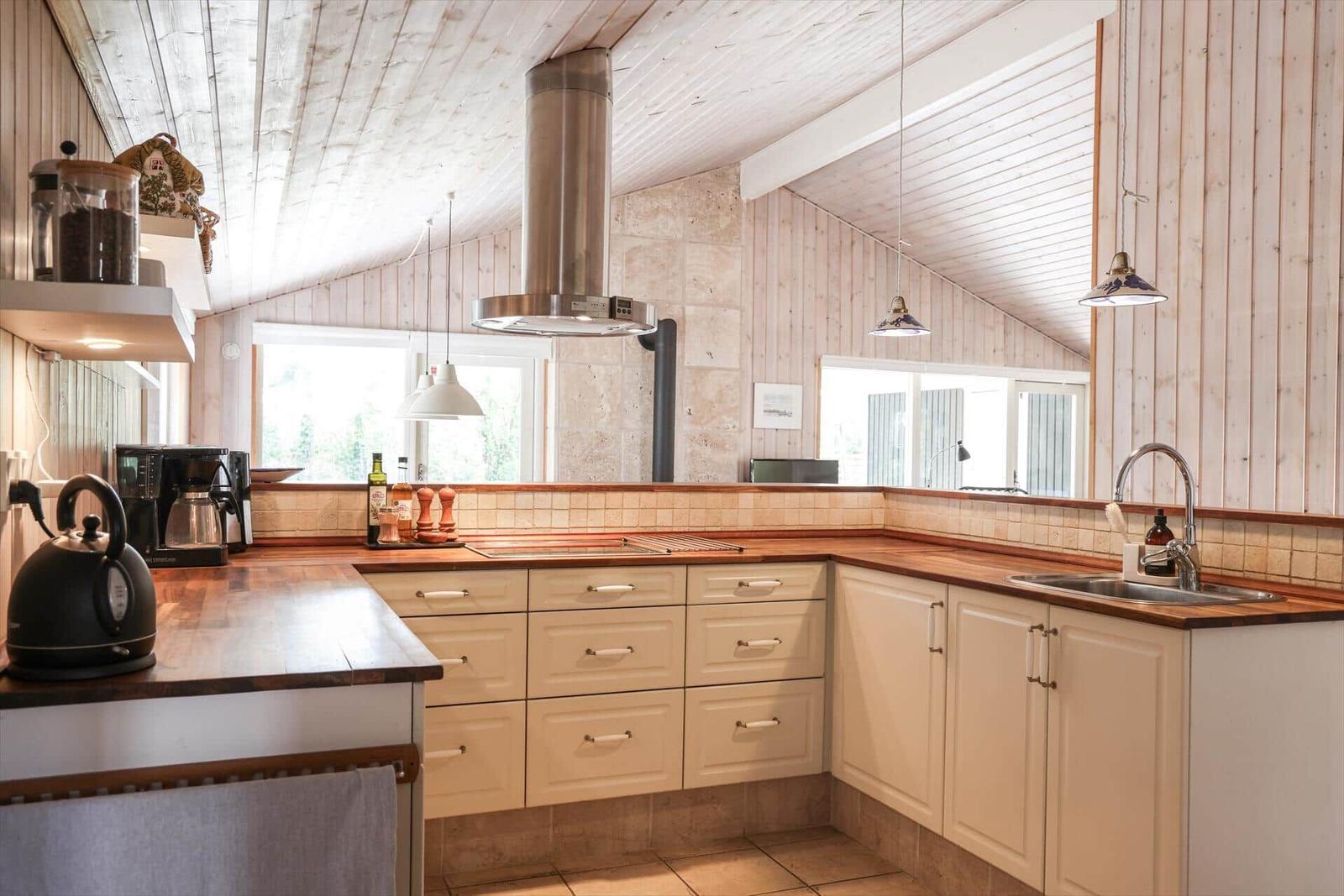 Kitchen with wooden walls, stainless steel extractor, and wooden surfaces.