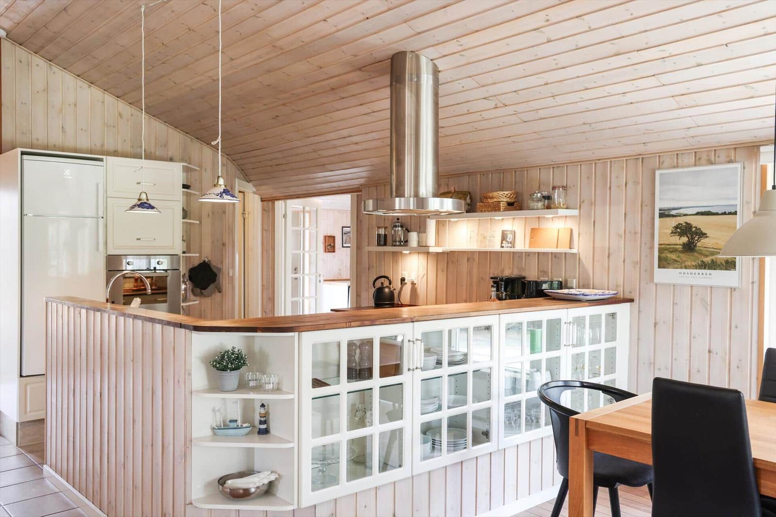 Kitchen with wooden walls and ceiling, white cabinets, and dining area.
