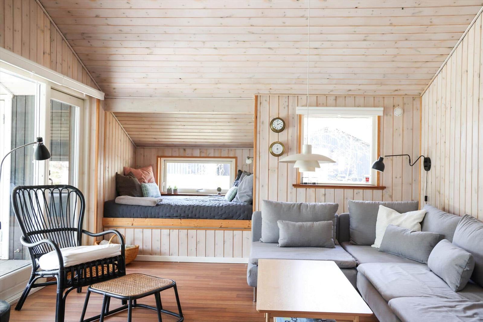 Living room with sofa, chair, and bed under sloped ceiling.