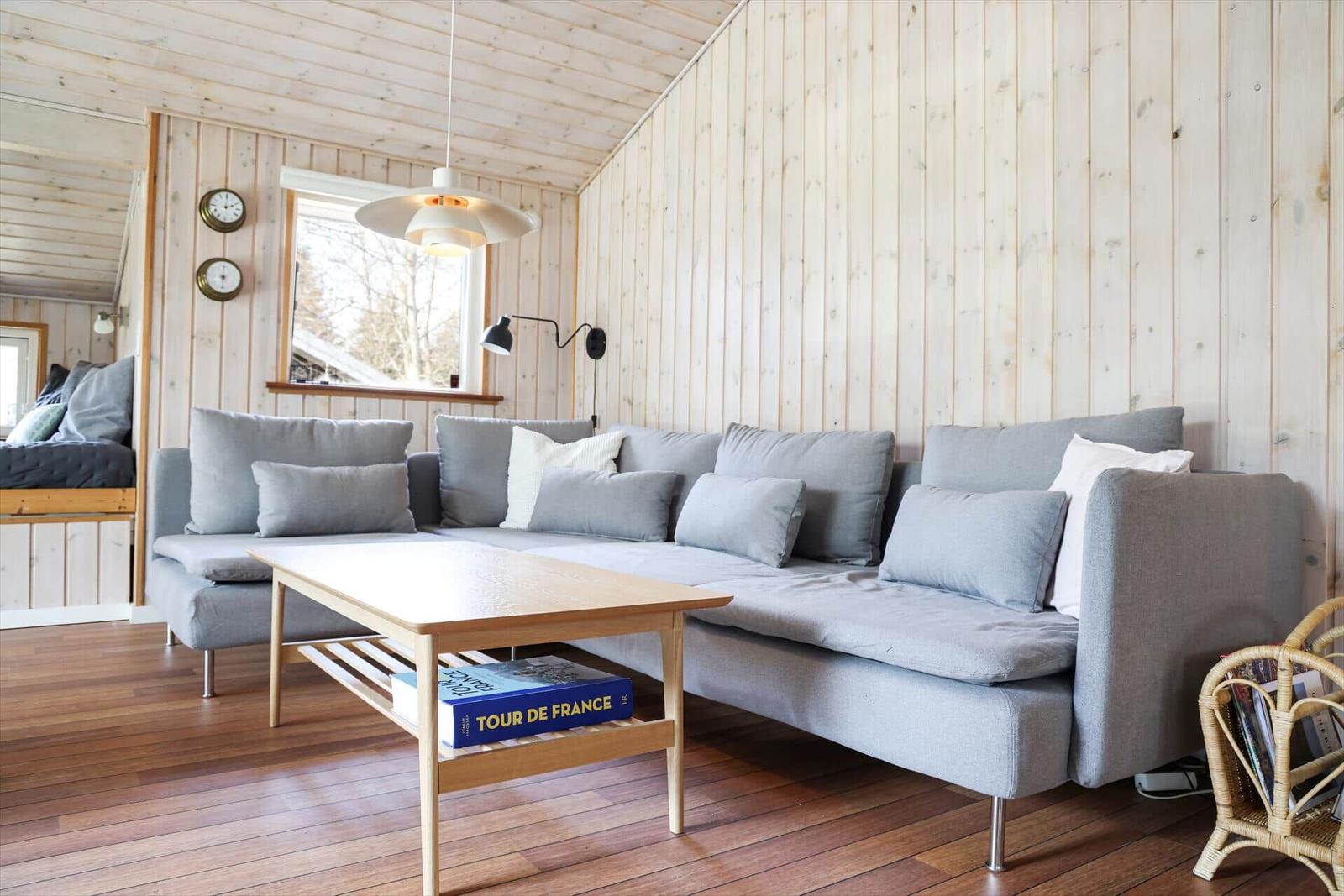 Living room with gray sofa, wooden table, and wooden walls.