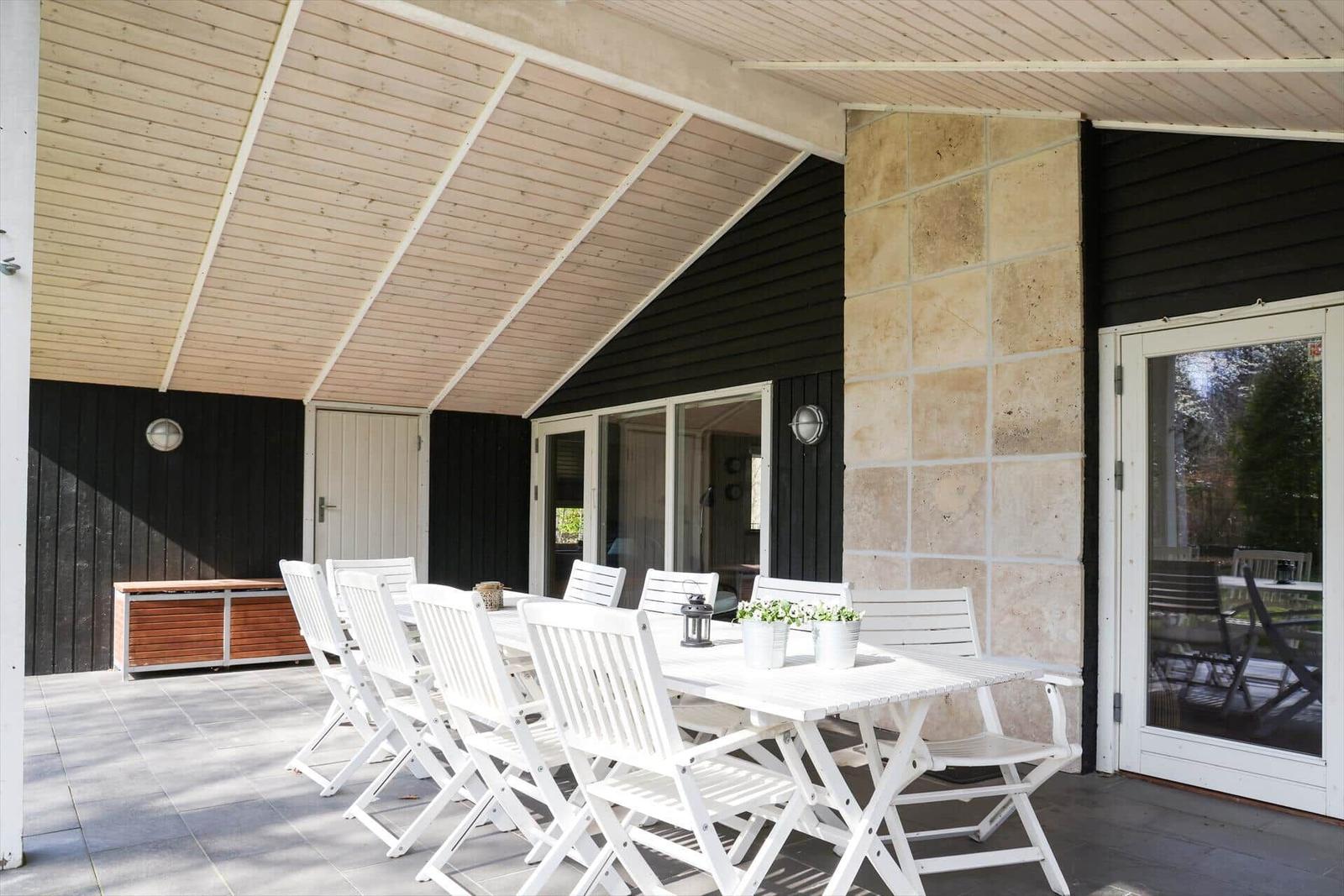Patio with white table and chairs under wooden roof