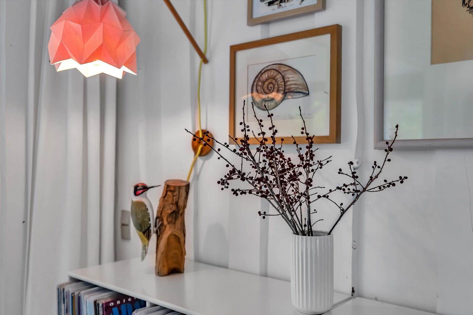 Ein Regal mit Vase, Vogeldekoration und Bildern an der Wand.