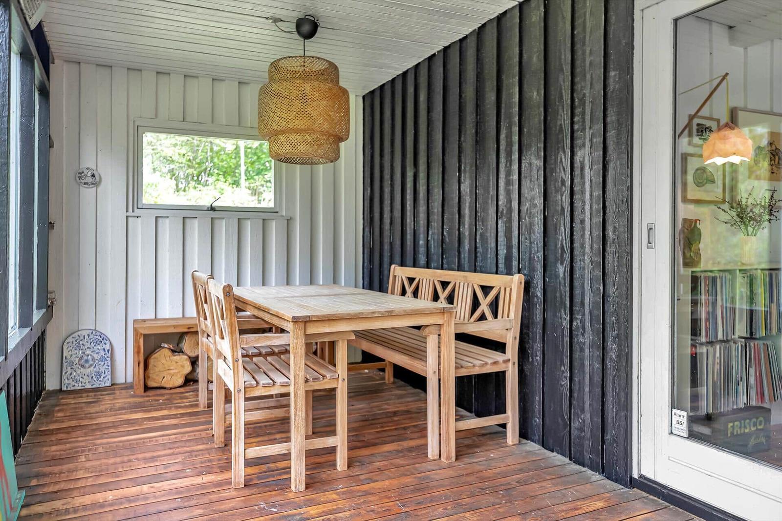 Holztisch mit Stühlen und Bank unter einem Korblicht.