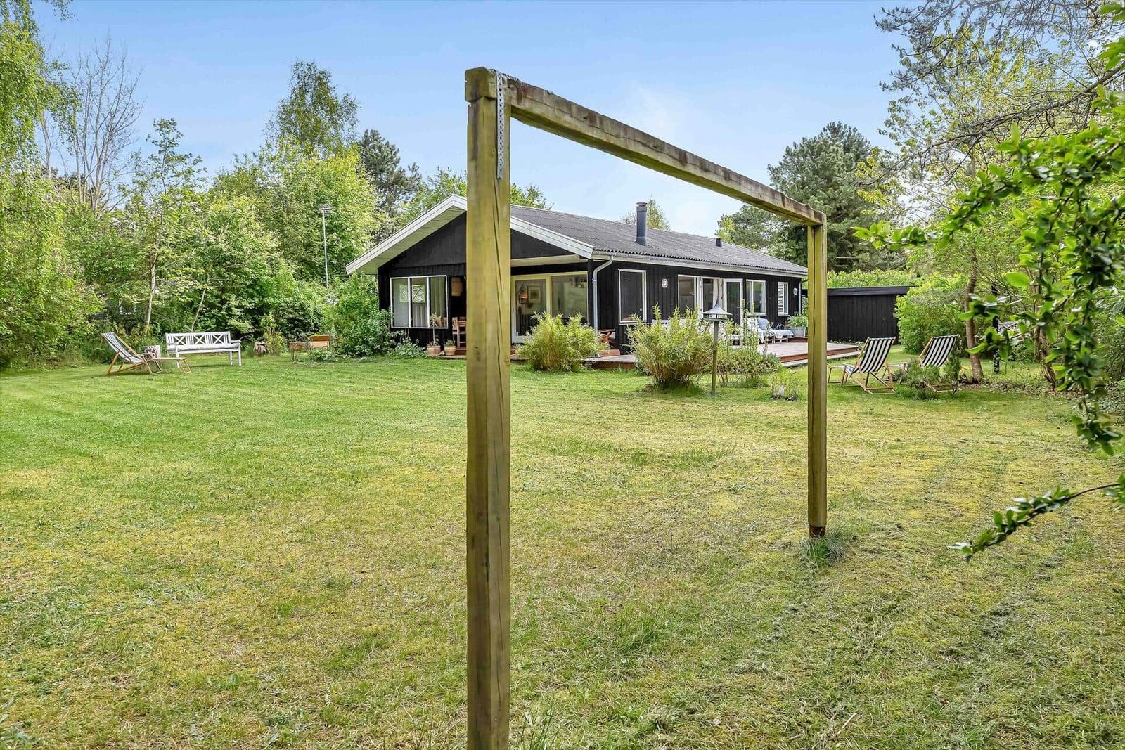 Schwarzes Haus mit großem Garten und Liegeflächen im Freien.