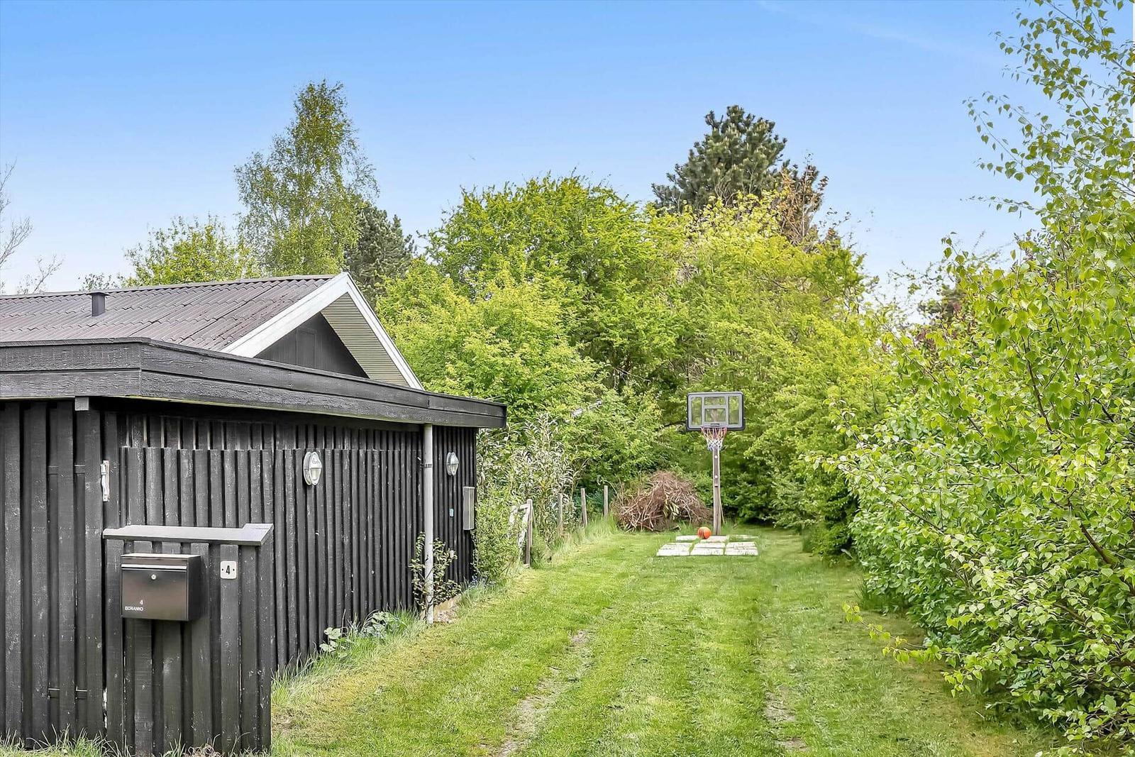 Haus mit grünem Garten und Basketballkorb im Hintergrund.