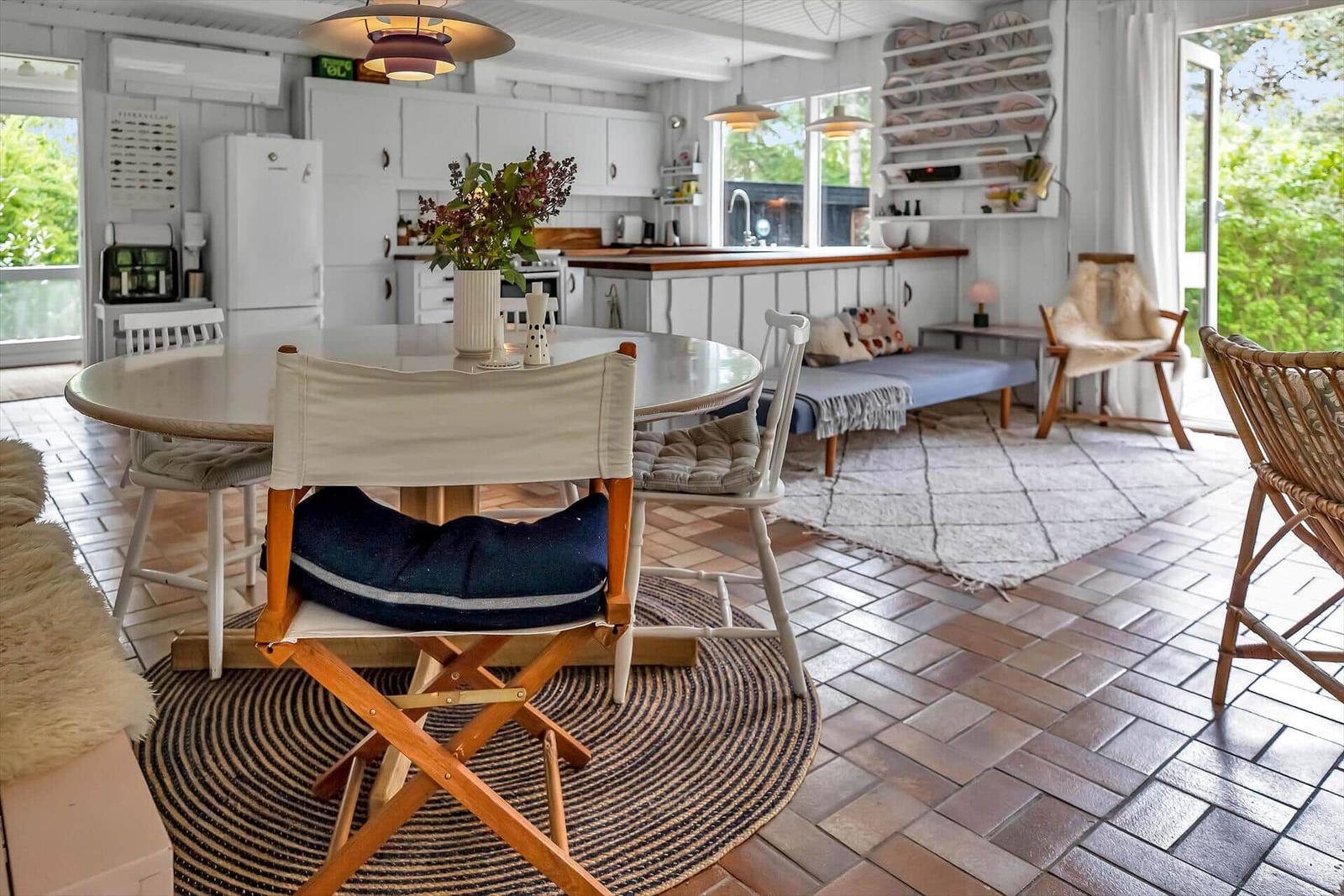 Ein Essbereich mit Tisch und Stühlen, Küche und Sitzgelegenheit im Hintergrund.