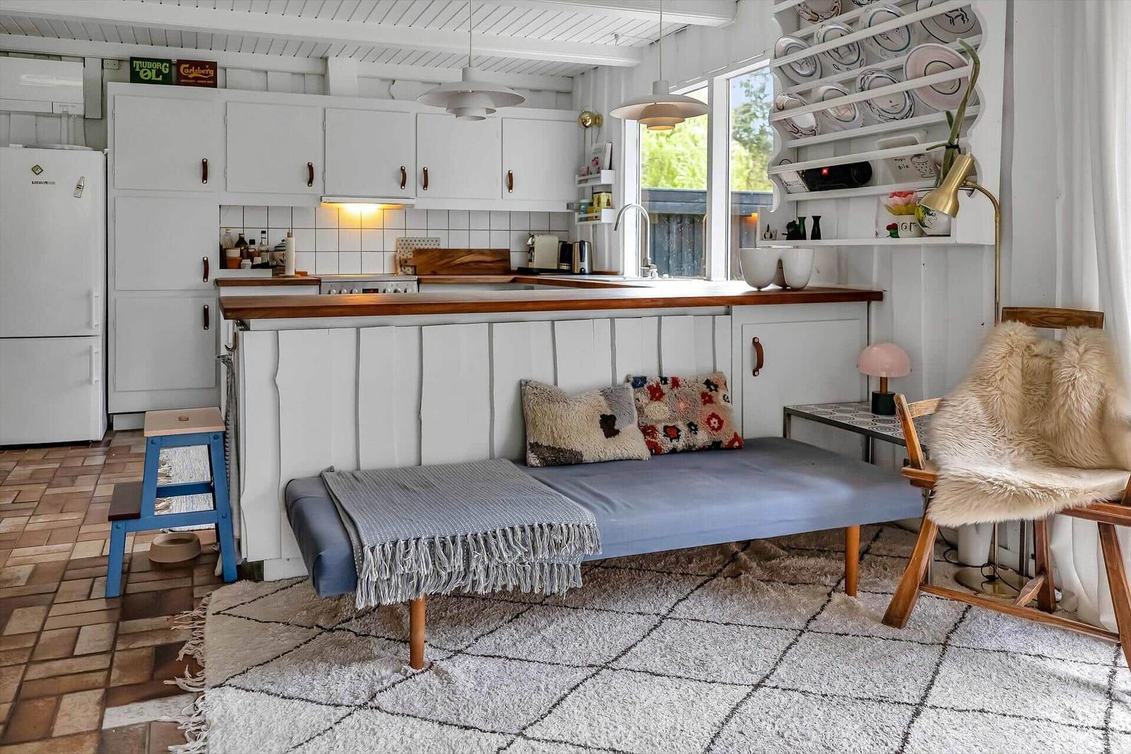 Küche mit Essbereich und Schlafsofa. Holzoberfläche und weiße Schränke.