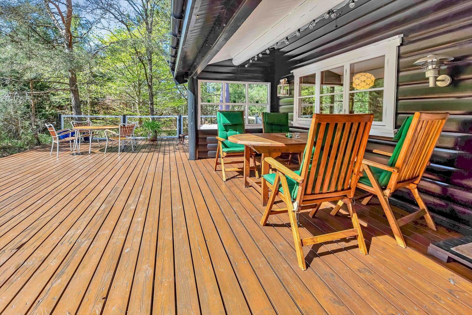 Holzterrasse mit Sitzgruppe und Blick in den Wald.