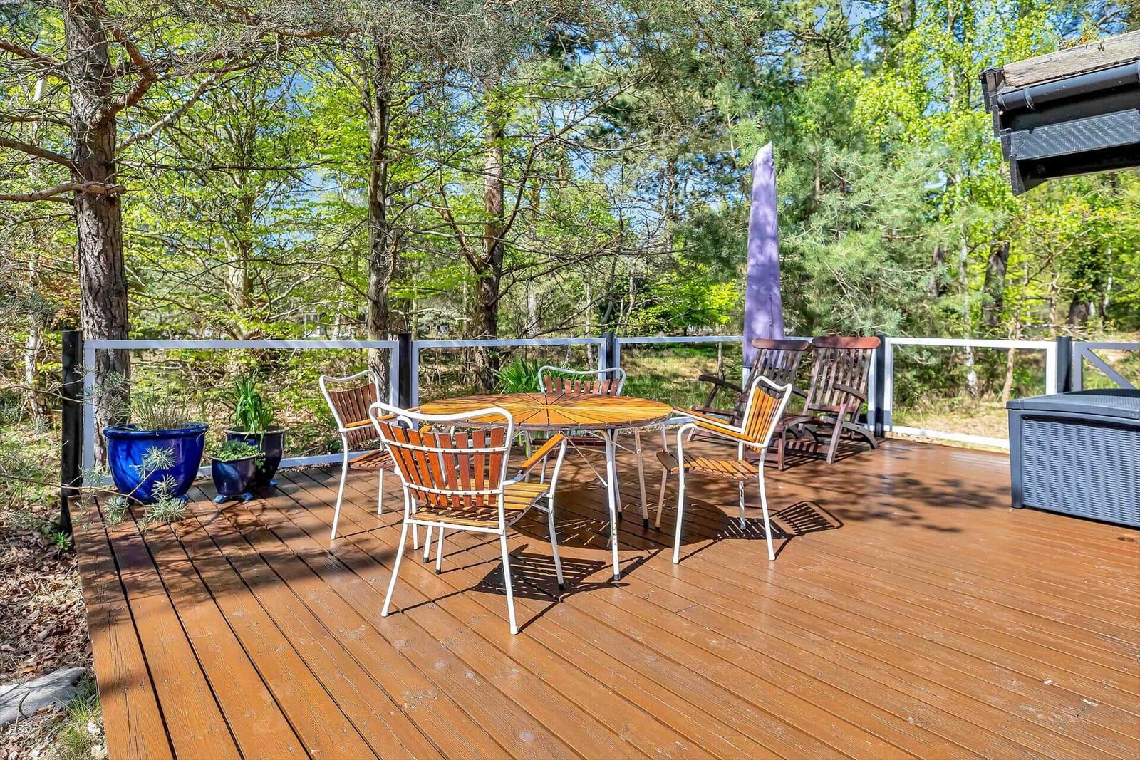 Terrasse mit Tisch, Stühlen und Sonnenschutz im Wald